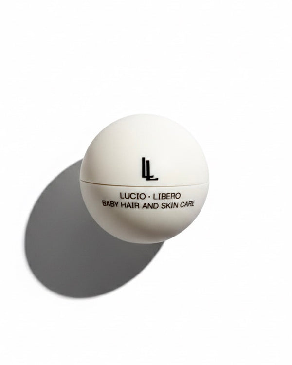 A white spherical cosmetic container labeled 'LL LUCIO - LIBERO BABY HAIR AND SKIN CARE' on a clean white background with a soft gray shadow.